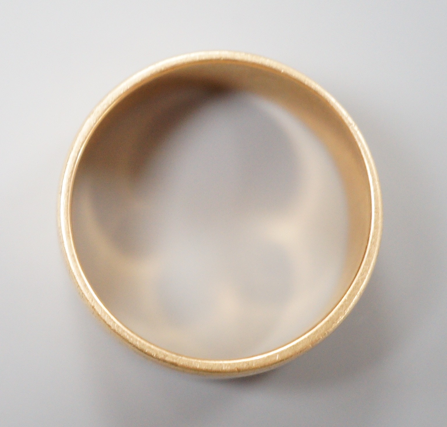 A yellow metal wedding band, unmarked, size P, 7.4 grams.
